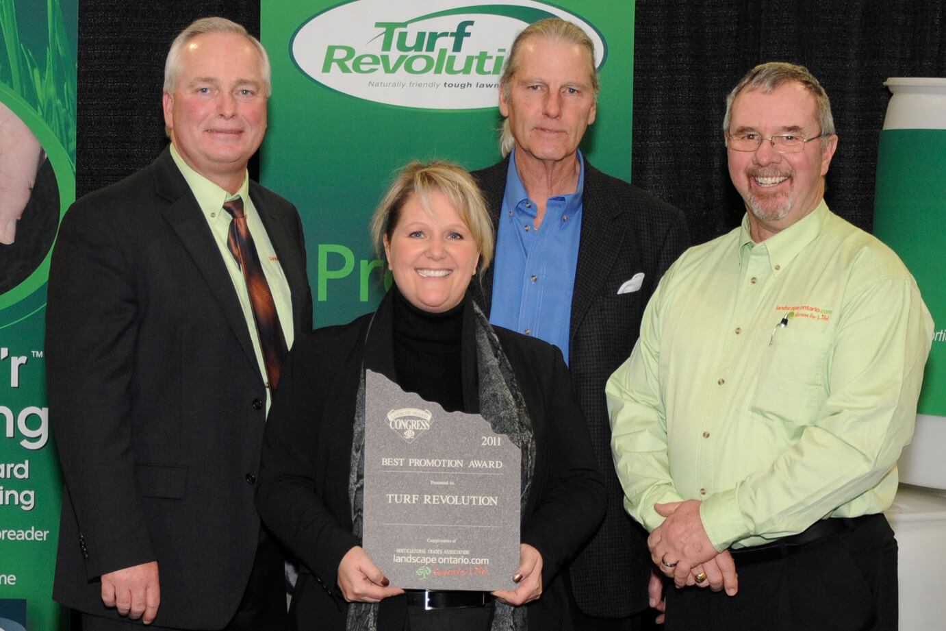 woman holding an award flanked by three men