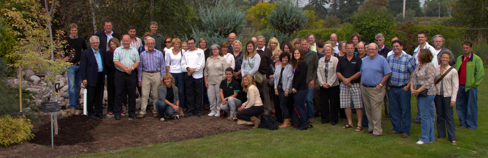 people standing around a newly-planted tree